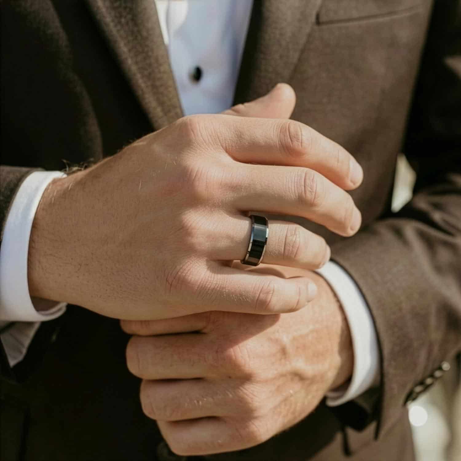 Dressed smartly in a brown suit, the man is wearing a black and silver tungsten ring on his hand.