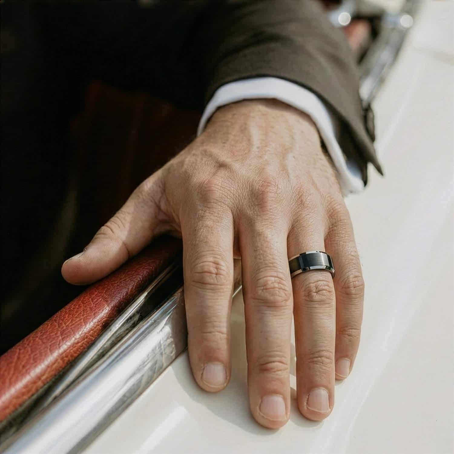 Resting his arm out of the car window, the mans hand is on display, showing his black and silver tungsten ring.