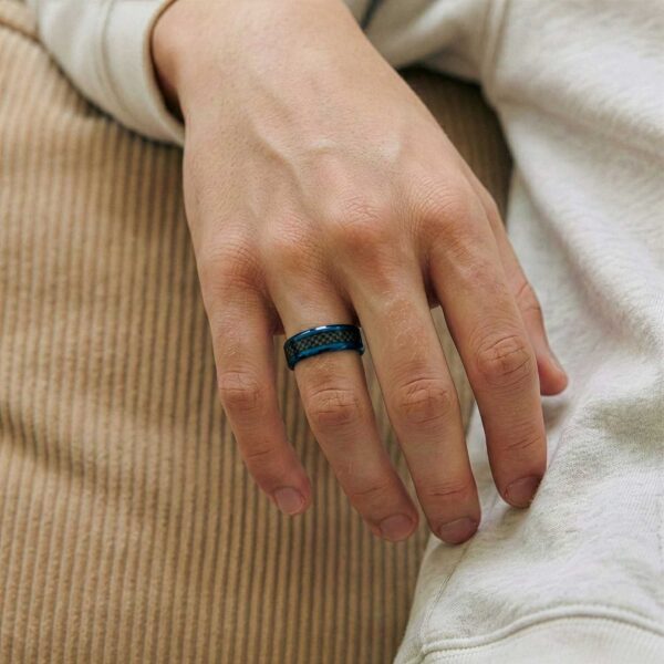A close up of a man's hand wearing a blue and black tungsten and carbon fibre wedding ring.