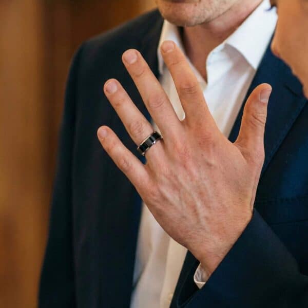 At the wedding ceremony, the man raises his hand showing his black and silver tungsten ring.