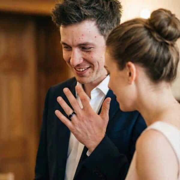 Full of smiles, the newly wed couple admire the mans ring, a black and silver tungsten band.