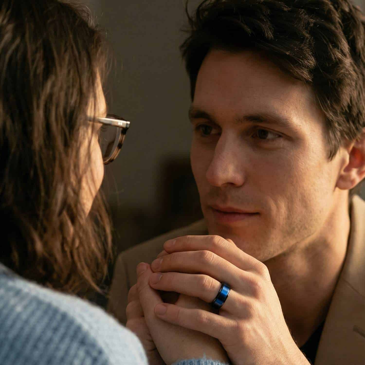 Couple holding hands with man wearing black tungsten ring with blue centre.