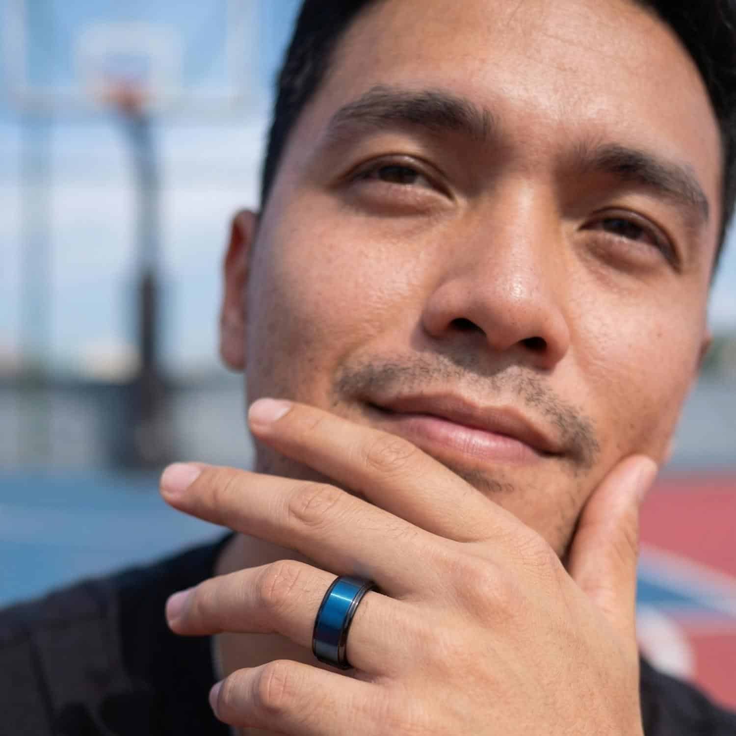 Man smiling with hands to chin wearing black tungsten ring with blue centre.