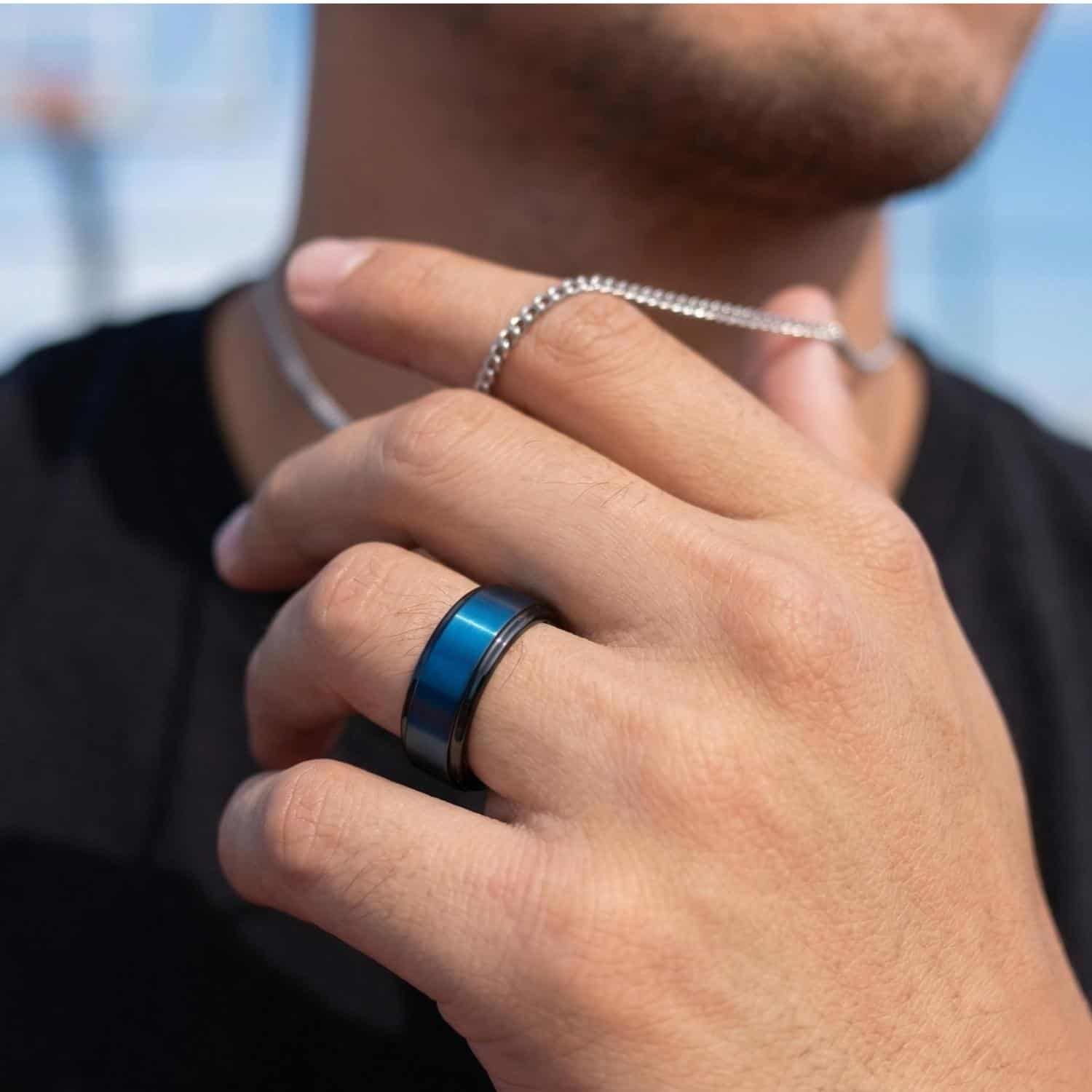 Close-up of a man’s hand wearing a black tungsten ring with a blue centre