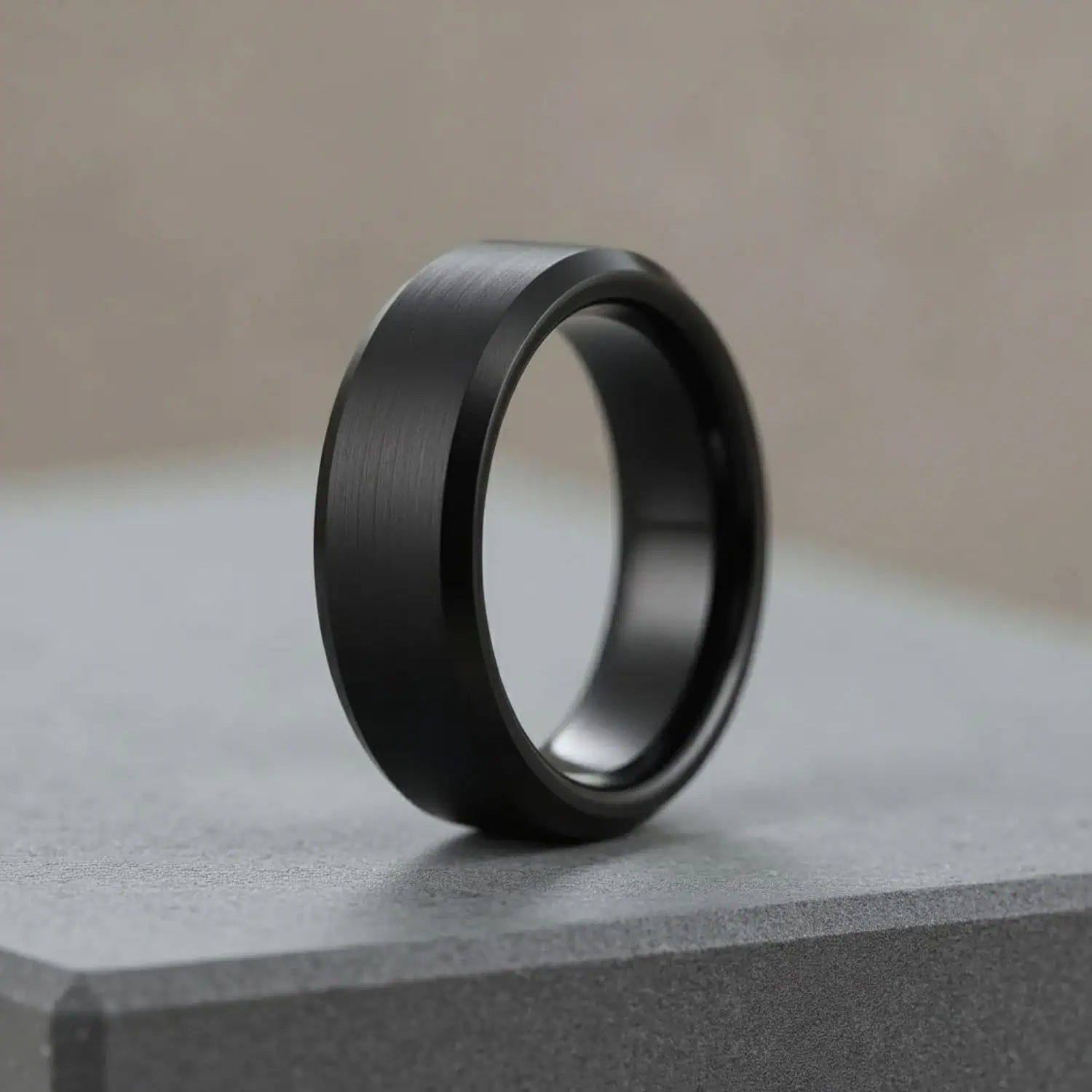 Close-up of brushed black tungsten ring with polished edges on smooth grey surface