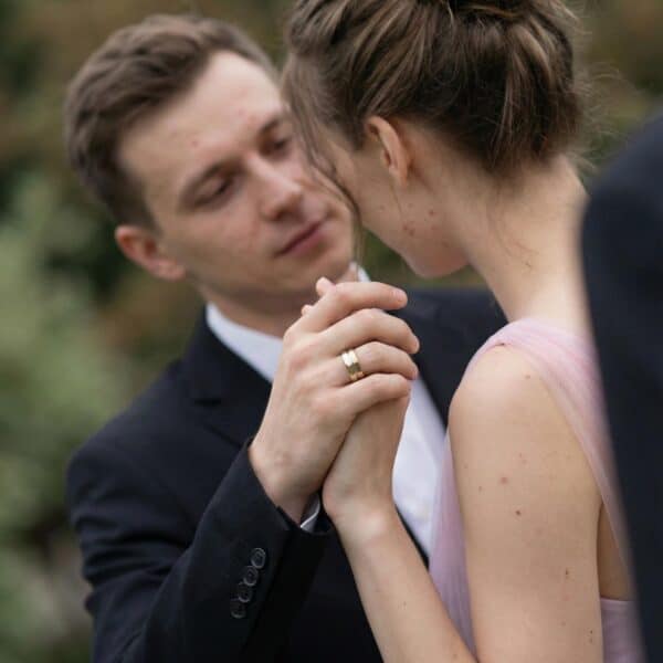 After the wedding ceremony, a couple share a special moment together. Holding hands, you can see the mans new wedding band. It is a gold and silver ring made with tungsten.