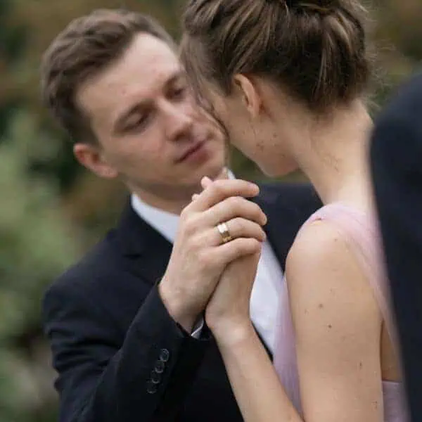 After the wedding ceremony, a couple share a special moment together. Holding hands, you can see the mans new wedding band. It is a gold and silver ring made with tungsten.