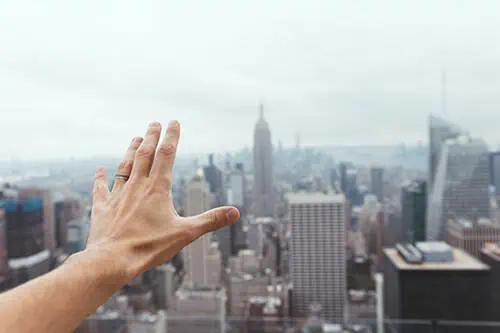 Men wearing ring stretches hand out over city skyline