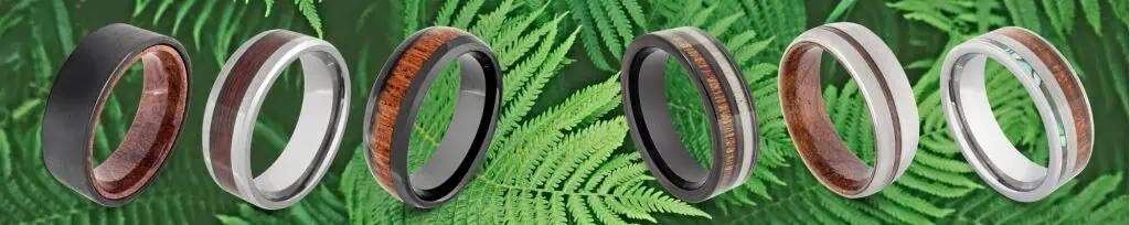 Selection of natural wood rings for men against backdrop of lush green fern leaves