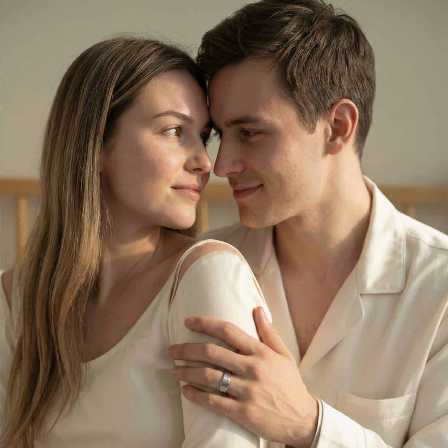 A couple embrace and gaze into each other's eyes. The man wears his new wedding band - a silver tungsten ring with a mix of brushed and polished finishes. The inside of the ring is bright red.
