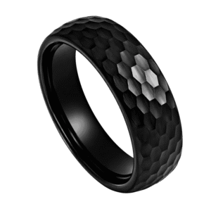 A close up image of a mans black ring. Made with tungsten, this black ring has a hammered effect finish. This means that the ring catches the light from many different angles.