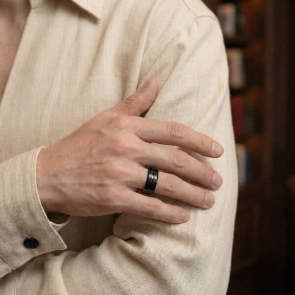 Dressed in a cream shirt, the man wears a black tungsten ring.