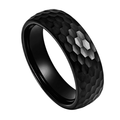 A close up image of a mans black ring. Made with tungsten, this black ring has a hammered effect finish. This means that the ring catches the light from many different angles.