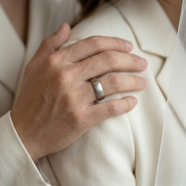 A brushed silver mens ring with a black inside. Close up on hand.