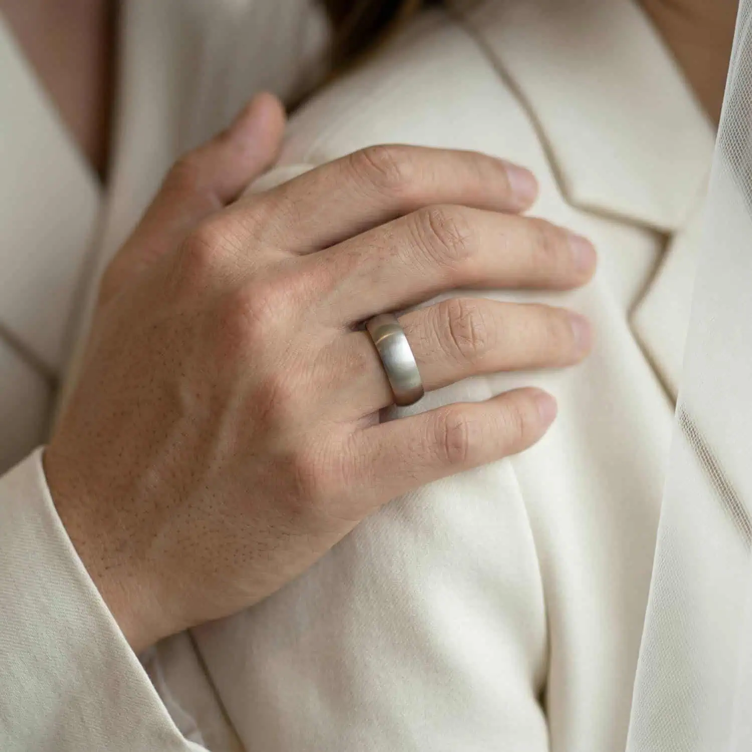 A brushed silver mens ring with a black inside. Close up on hand.