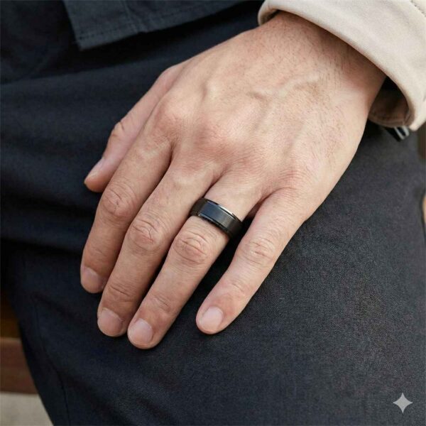 A close up image of a hand resting on a mans leg. On his hand is a black tungsten ring that has a rose gold interior.