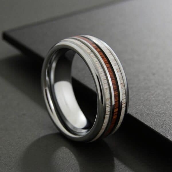 Men’s silver tungsten ring featuring whiskey barrel wood and natural antler inlays, suitable as a wedding band.