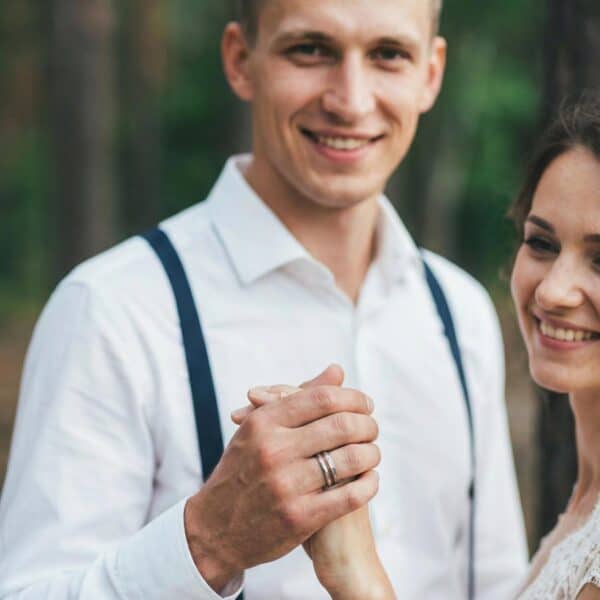 After the wedding ceremony, the couple hold hands. The man is showing his silver tungsten ring that is distinctive with its grooves of natural wood and antler.