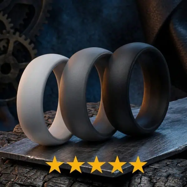 Set of three men's silicone rings in light grey, charcoal grey and black, displayed upright on a brushed silver surface with five stars beneath.
