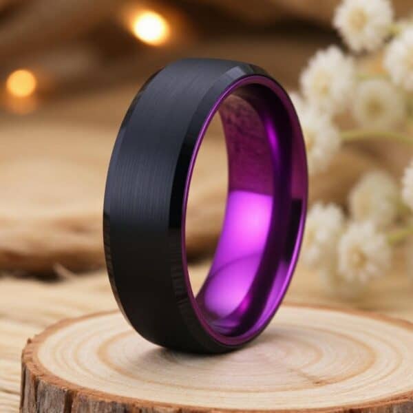 On a wooden stand, and with white flowers in the background, a ring stands upright and is the focal point of the photograph. It is a black tungsten ring that has a purple interior. The ring is black with a brushed finish, and the edges are polished.