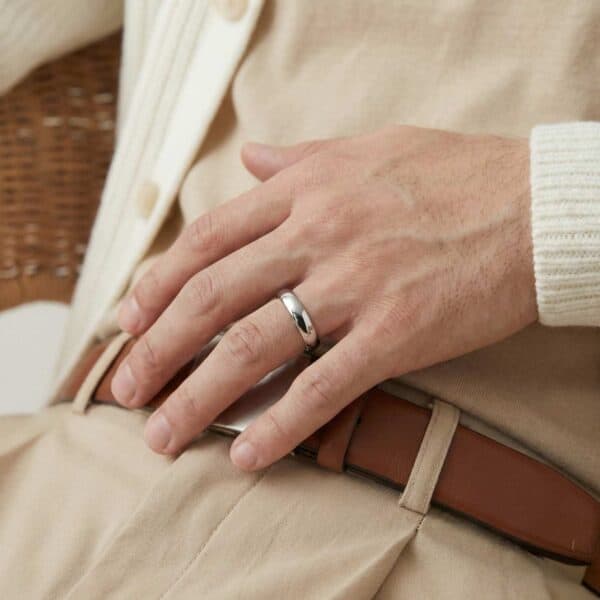 Resting his hand across his belt, the man is wearing a rig on his wedding finger. It is a thin style silver tungsten band.