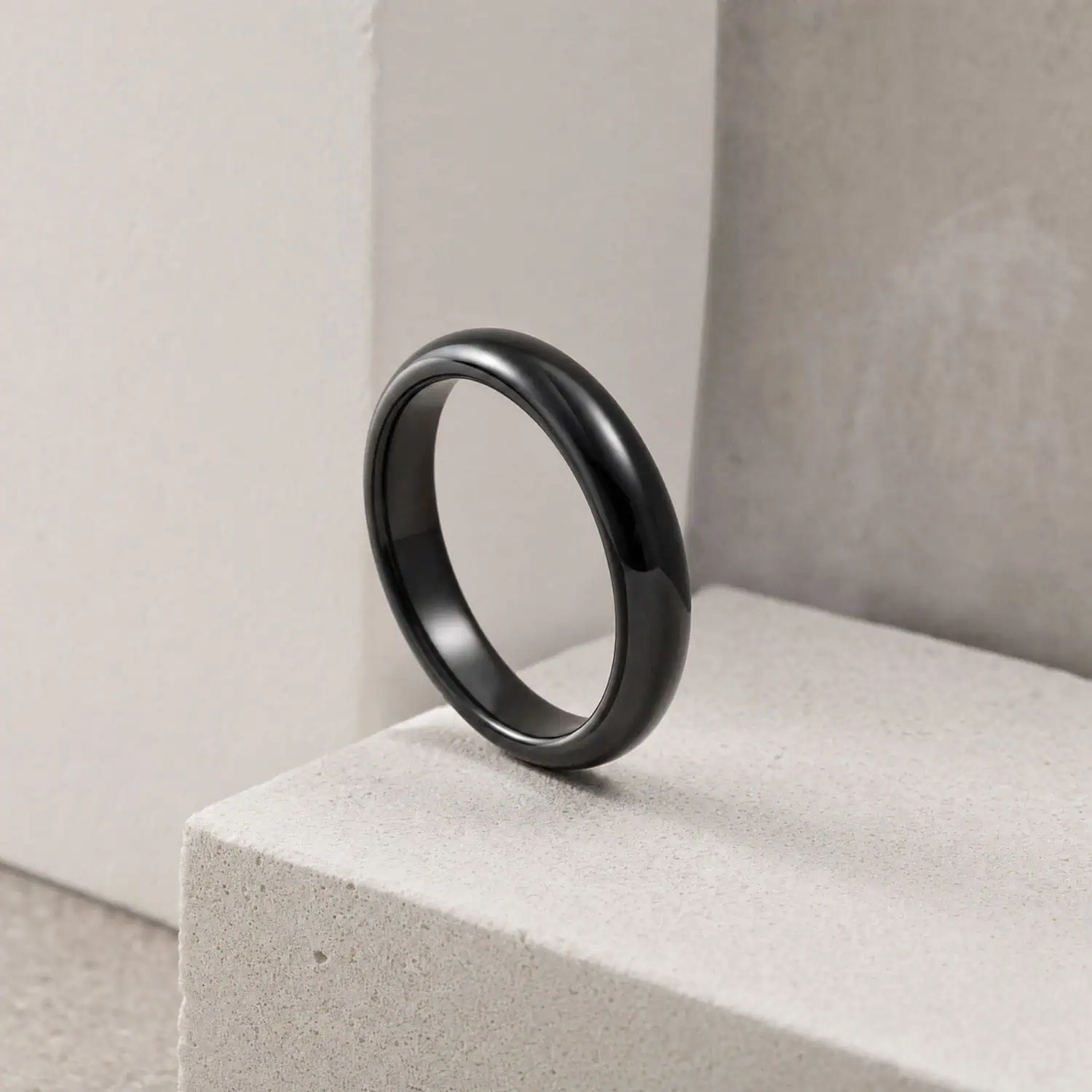 Minimalist black ceramic ring with a polished finish and slim 4mm profile, displayed against a clean white background.