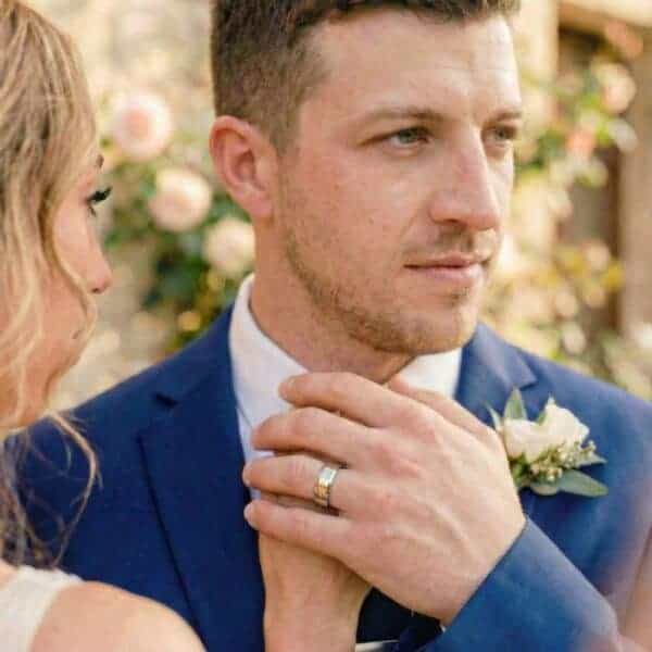 During the wedding ceremony, the groom looks to one side. Holding the hand of his new wife, you can see his silver tungsten ring that features a groove of gold.