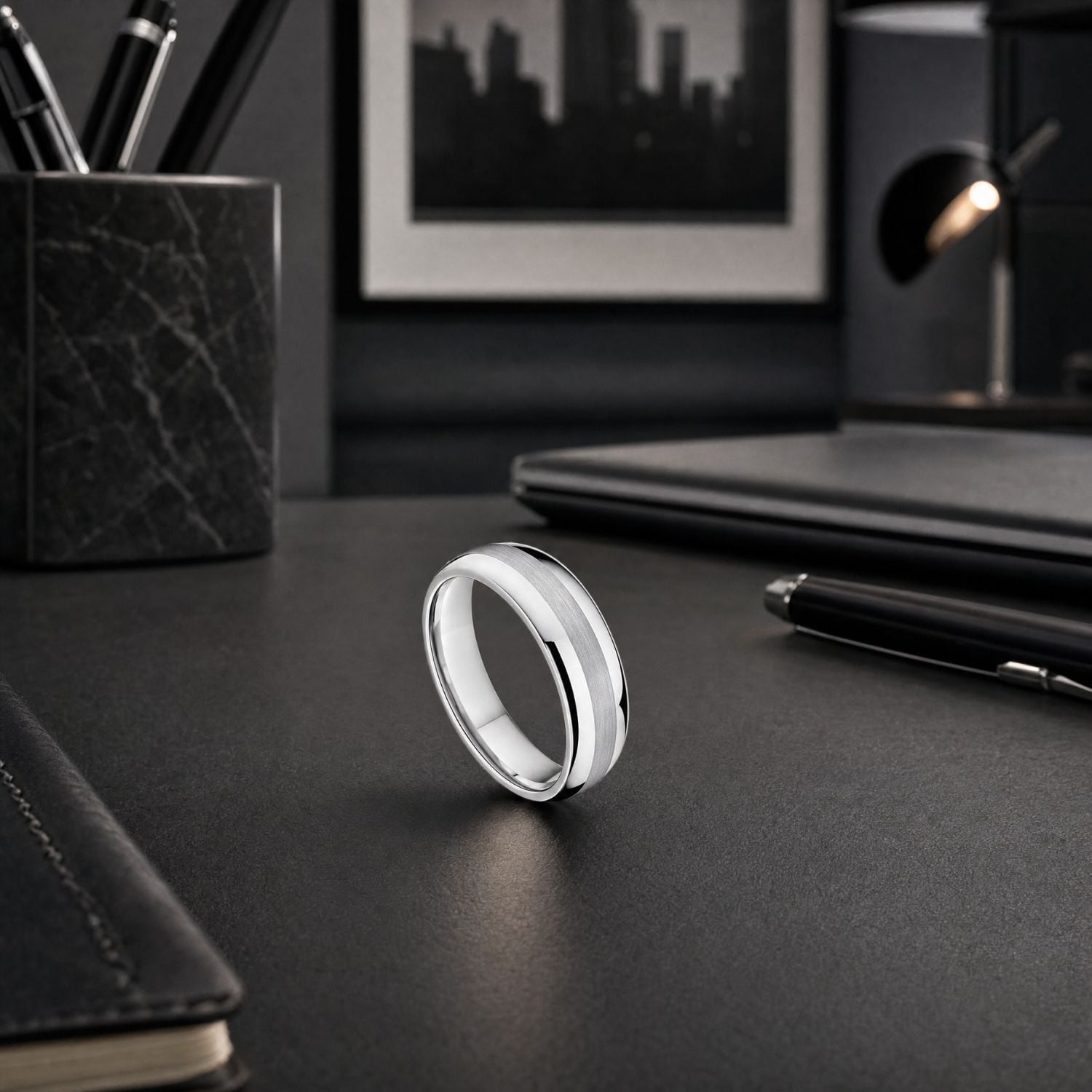 The Knight 8mm silver tungsten ring standing upright on a modern office desk, showcasing its brushed centre and polished silver finish.