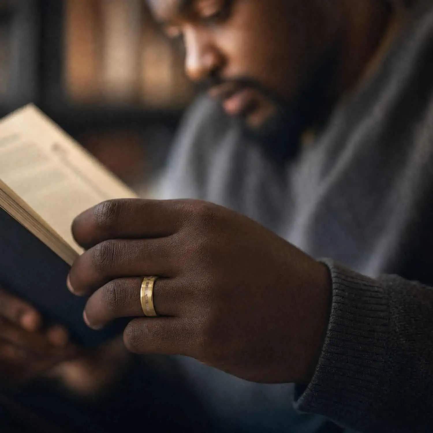 Man reading a book while wearing the Splendour gold tungsten ring with a textured hammered finish and natural antler inlay.