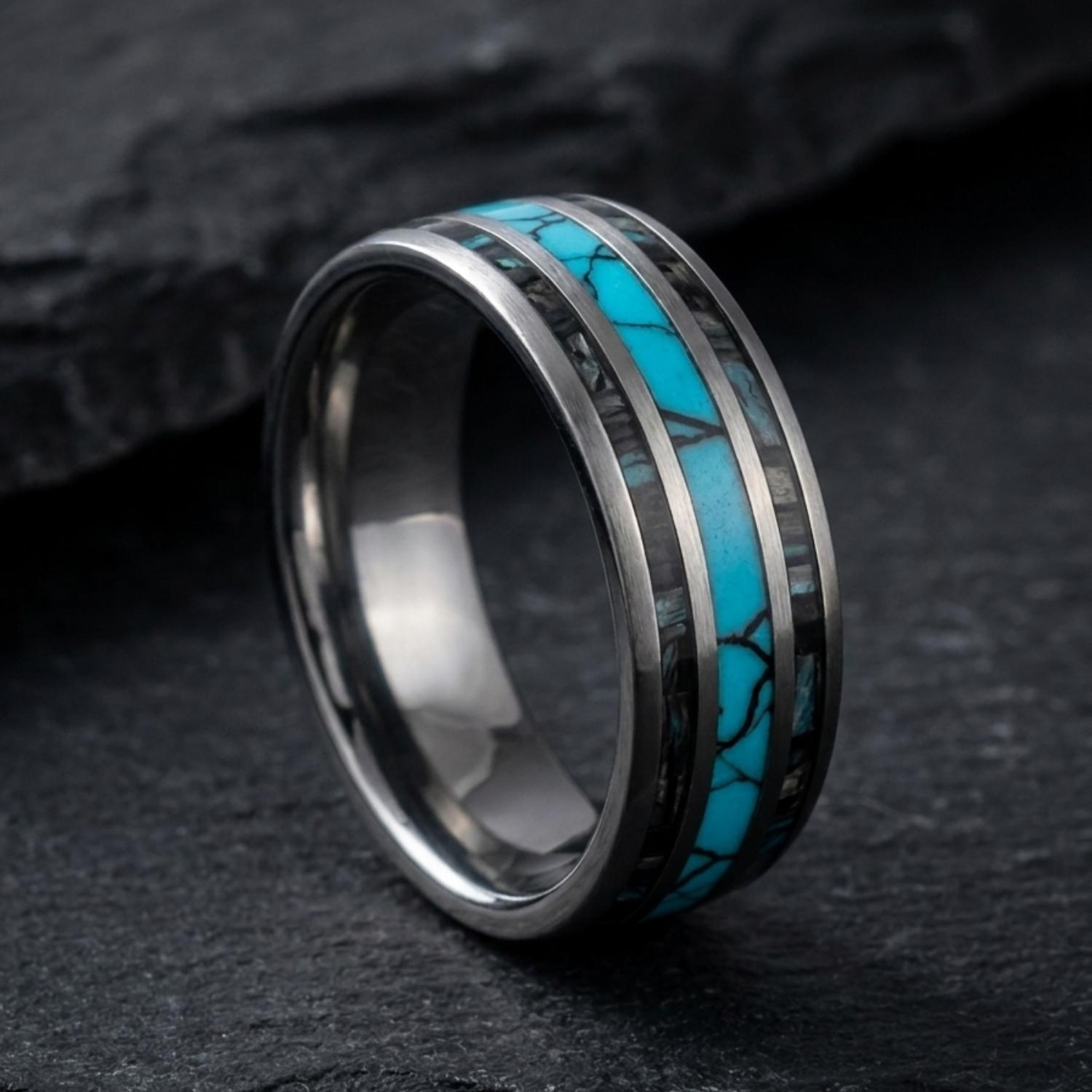 Rio polished silver tungsten ring standing upright on dark slate, showcasing its vibrant turquoise centre and natural abalone shell inlays.