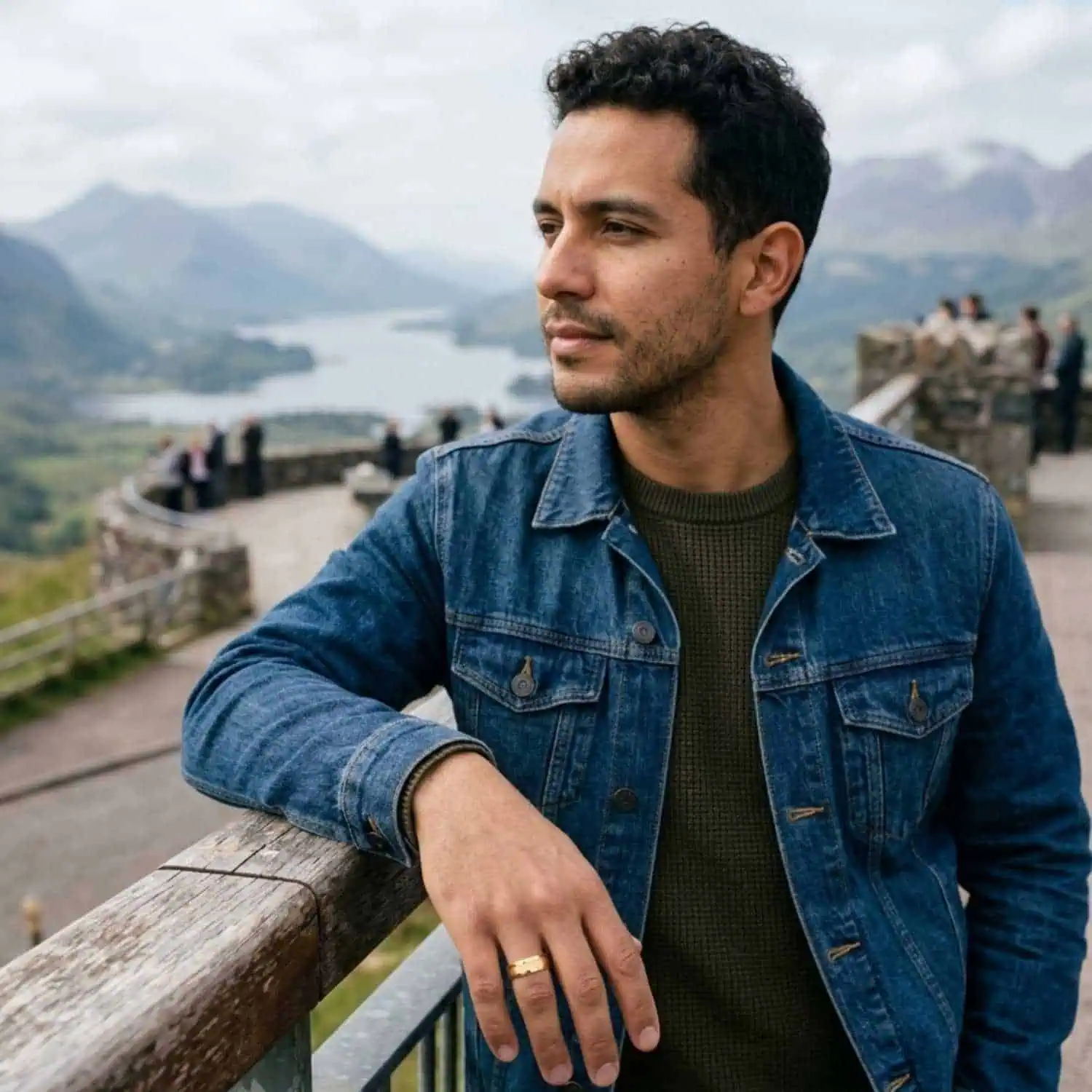 Man leaning on a wooden railing while enjoying the view, wearing the Valour gold tungsten ring with brushed sections and polished bevelled edges.