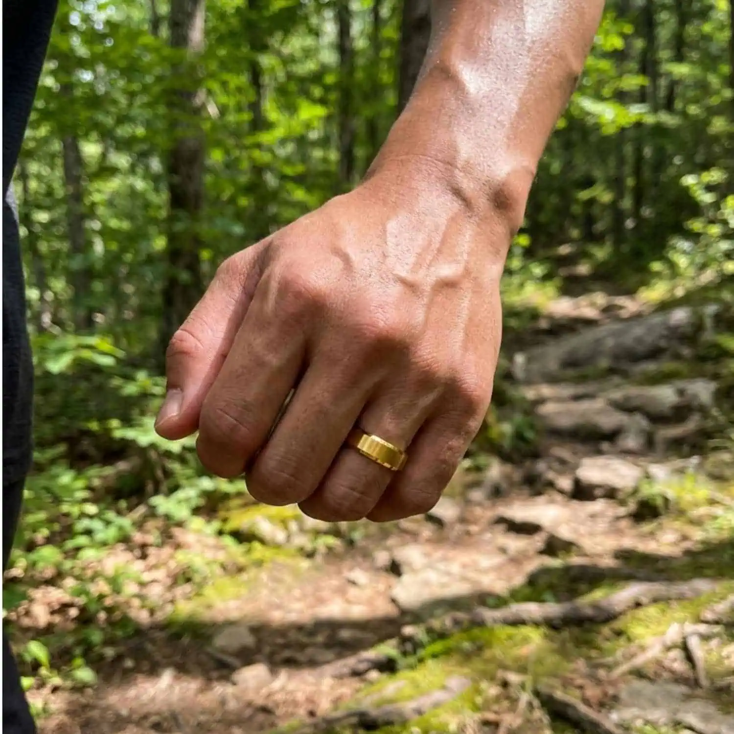 Man running through countryside trails while wearing the Regent men's brushed gold tungsten carbide ring with polished bevelled edges.
