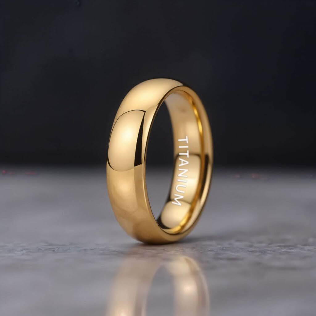 A polished gold titanium ring standing upright on a smooth marble surface, with the word “Titanium” engraved inside and a dark background.