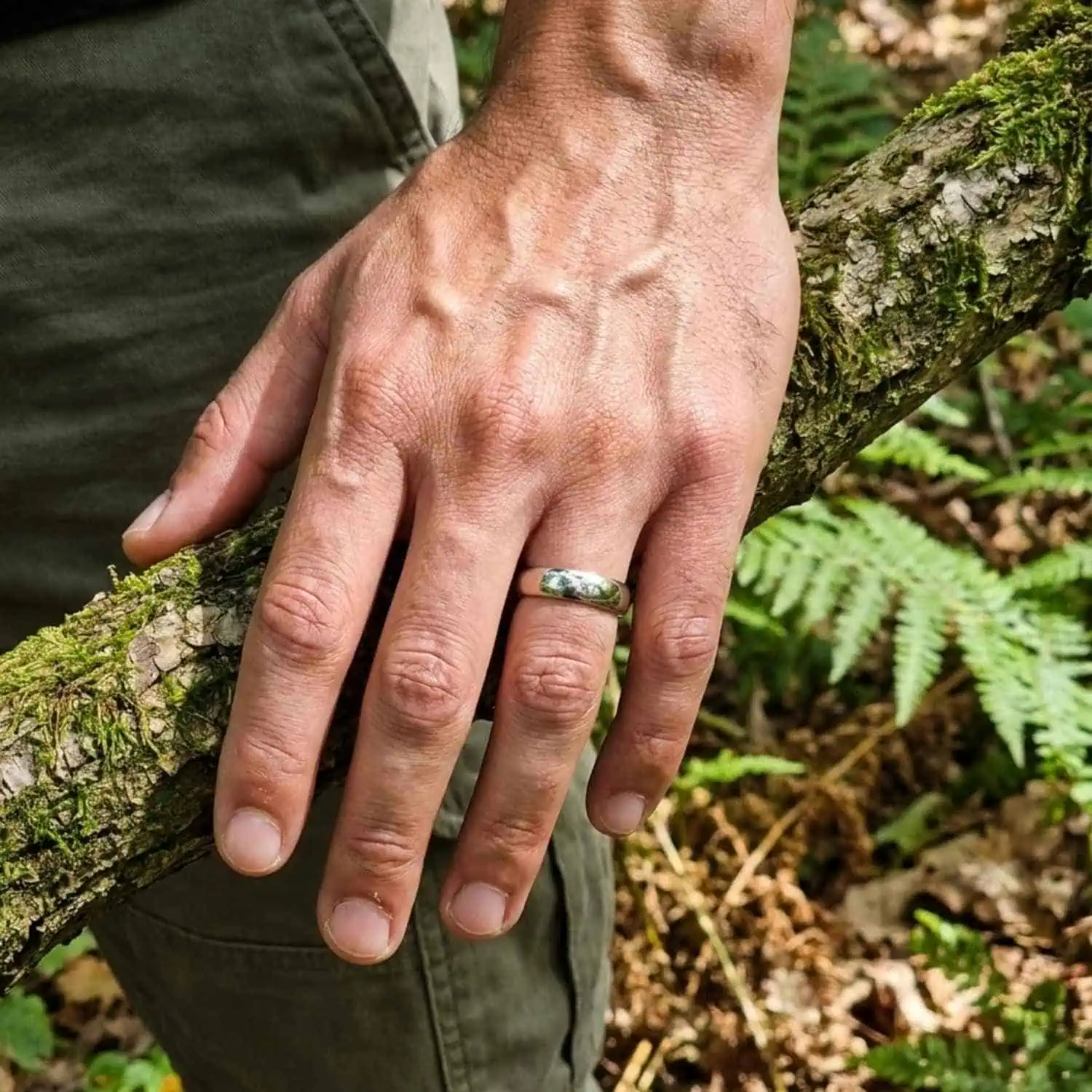 Man walking through a lush forest while wearing the Legacy polished white gold tungsten ring on his wedding finger.