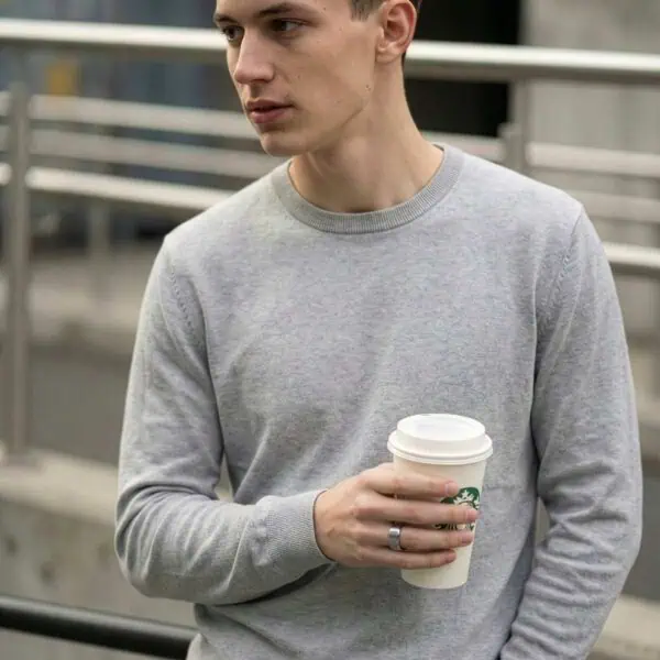 Carrying a cup of coffee, the man is wearing a white gold tungsten ring.