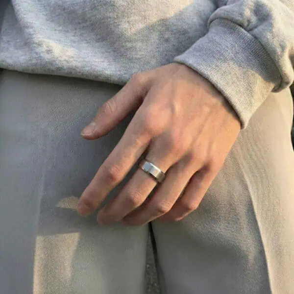 A man wears a white gold tungsten ring on his hand in this close up shot.