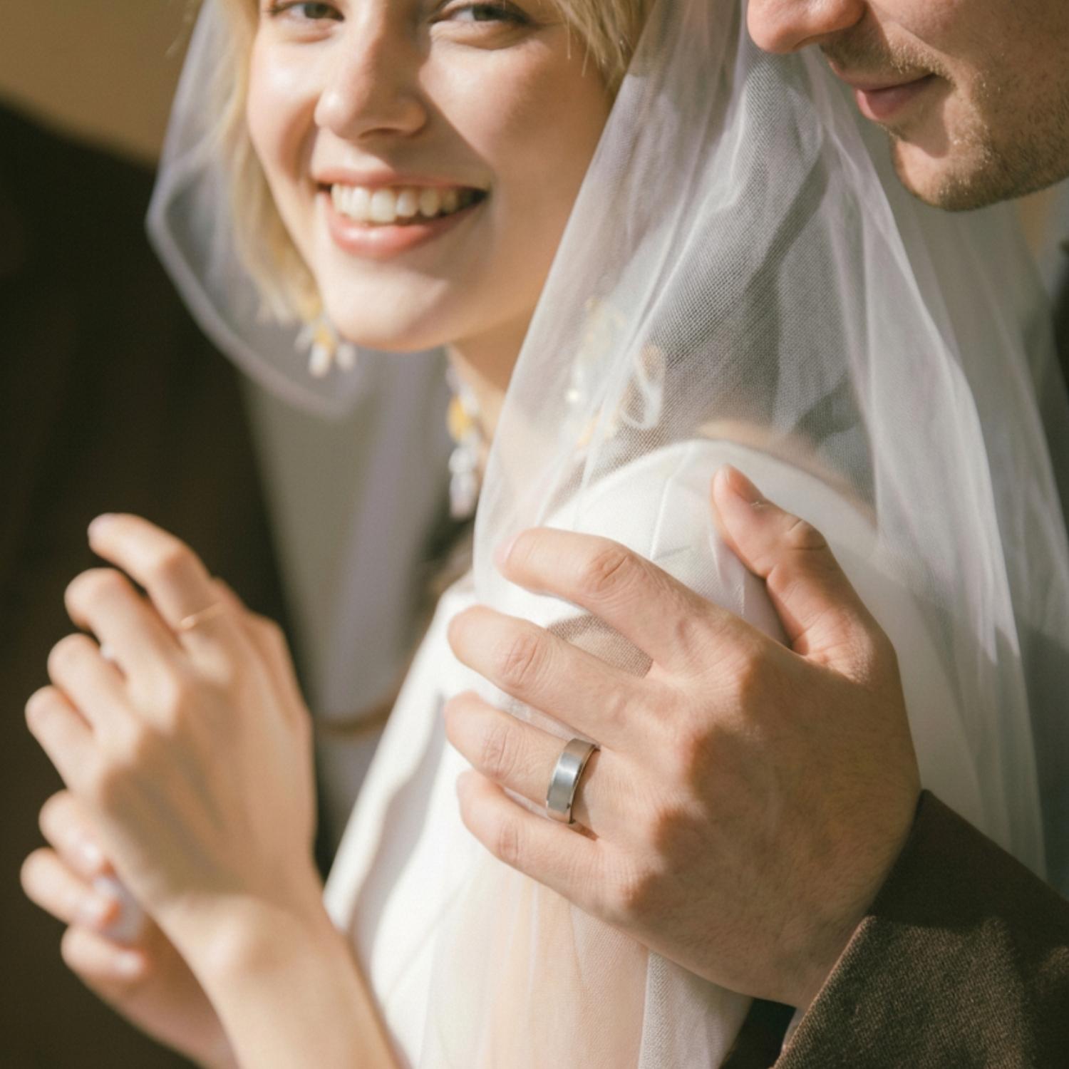 The newly wed couple stand close together, the man wearing a white gold tungsten ring.