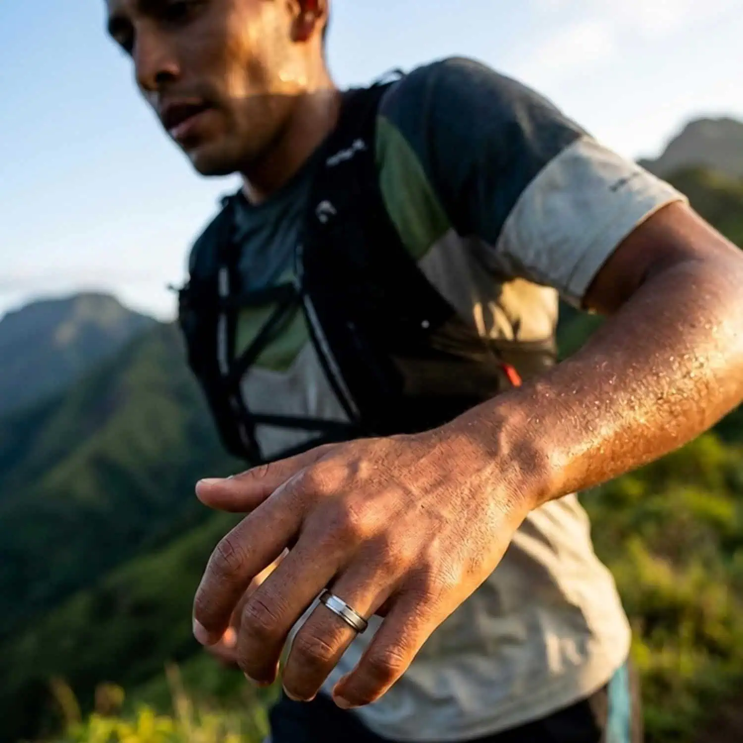 Runner crossing grassy hills while wearing the Titan Thin Style lightweight brushed silver titanium ring with polished stepped edges.