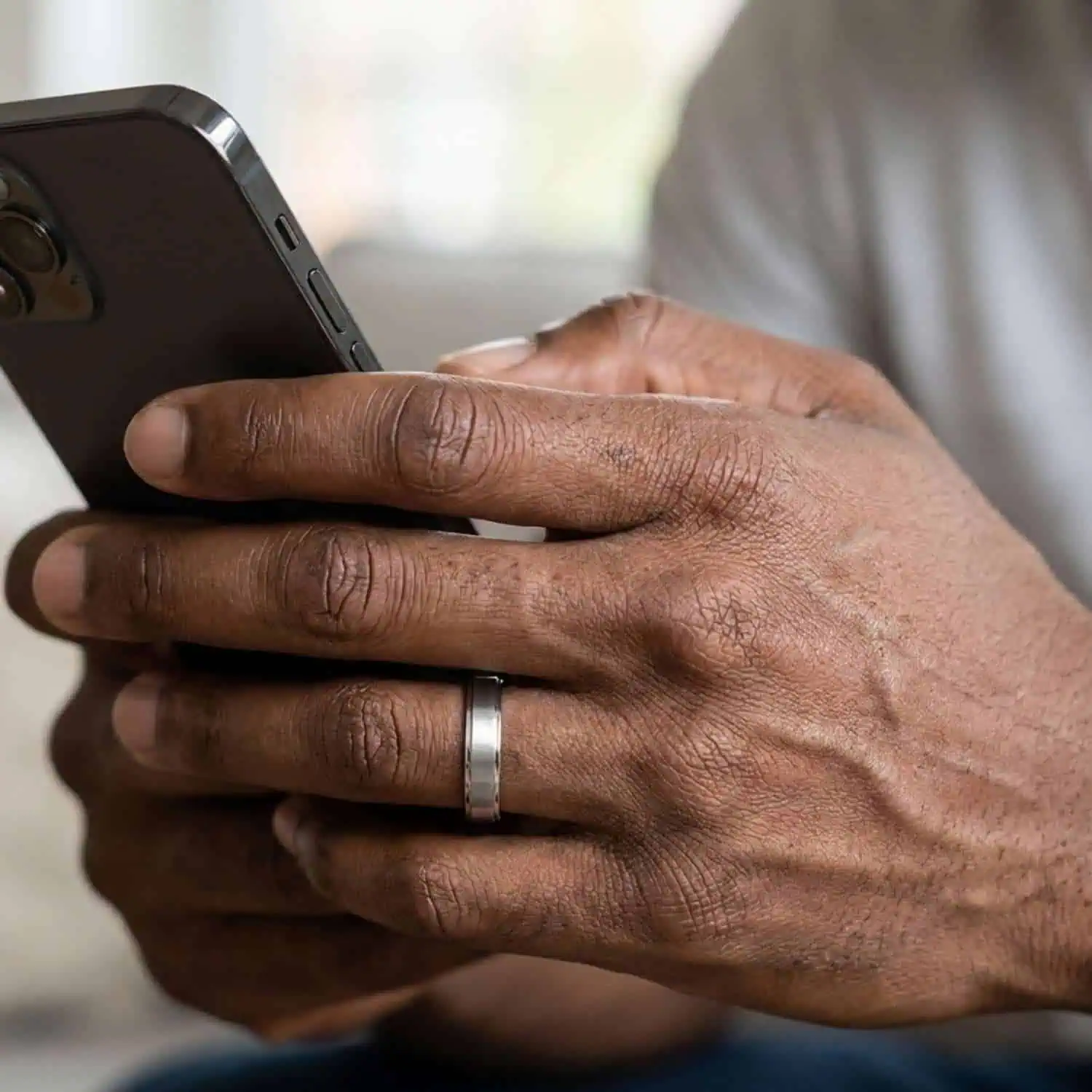 Man looking at his phone while wearing the Titan Thin Style men's brushed silver titanium ring with a raised centre and polished stepped edges.