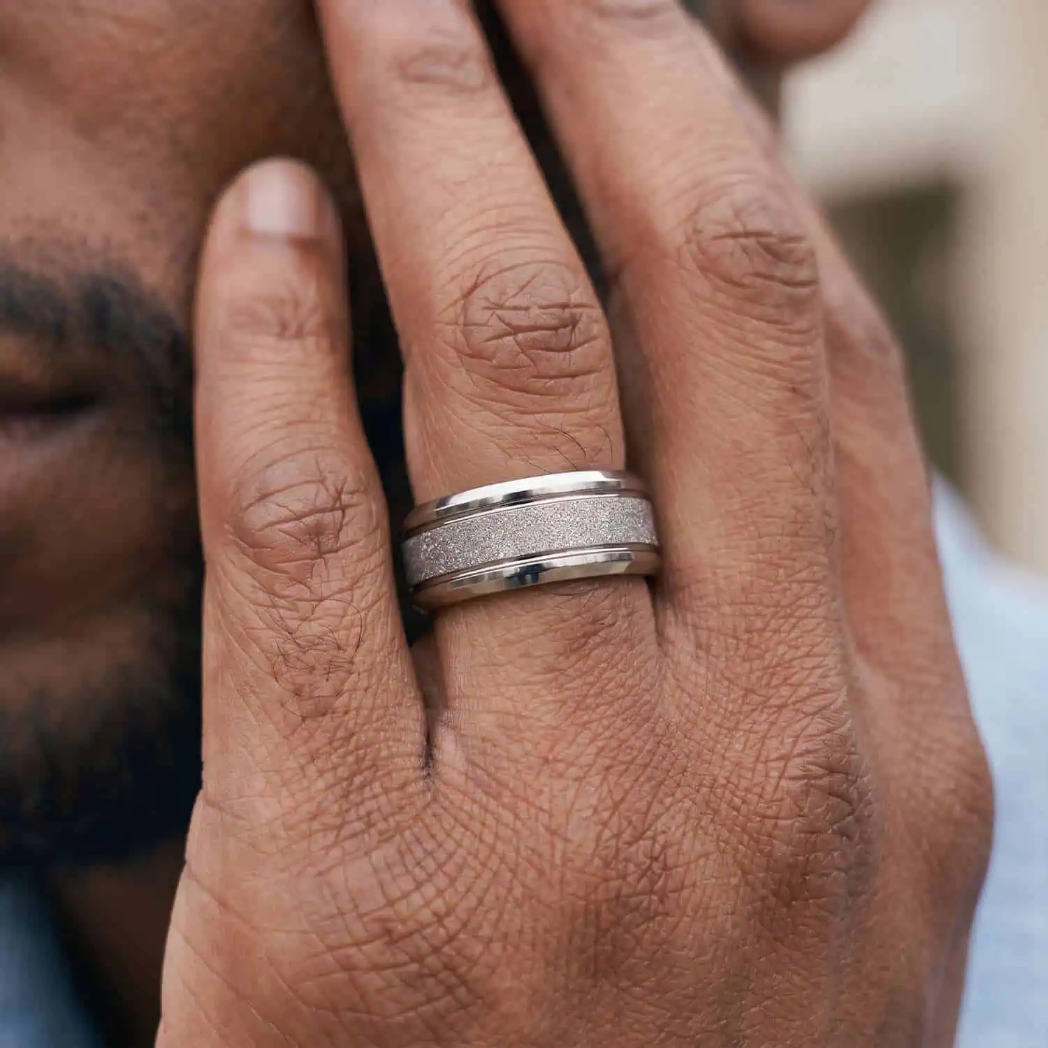 Close-up of a man's hand wearing the Vantage white gold tungsten ring featuring a lightly domed profile, sandblasted centre, and polished edges.