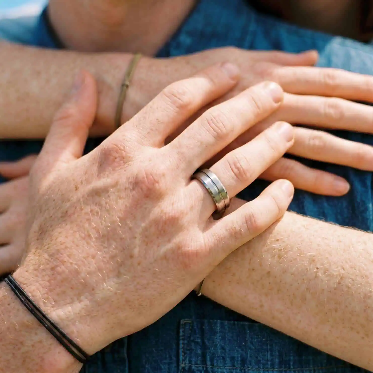 Close-up of a couple's hands with the man wearing the Zenith tungsten wedding ring featuring raised brushed sections and a polished centre groove.