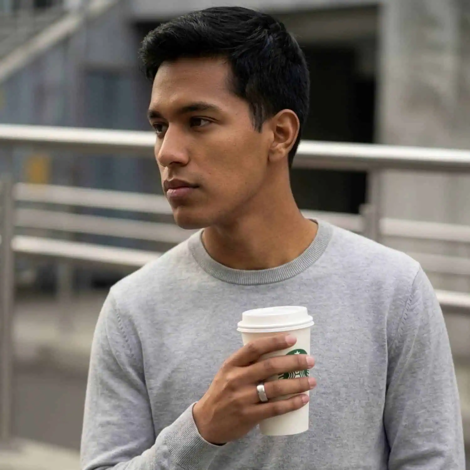 Man holding a cup of coffee while wearing the Crest men's white gold tungsten ring with a brushed centre and polished bevelled edges.