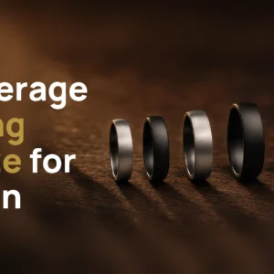 Five plain men's wedding bands in silver-coloured and black finishes, arranged from smallest to largest ring size on dark wood, with the title Average Ring Size for Men