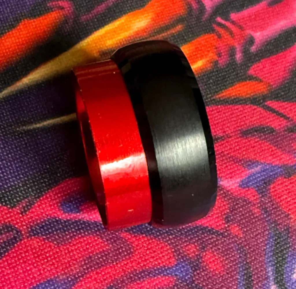 A two-colour ring whose red inner sleeve has separated from its black outer band