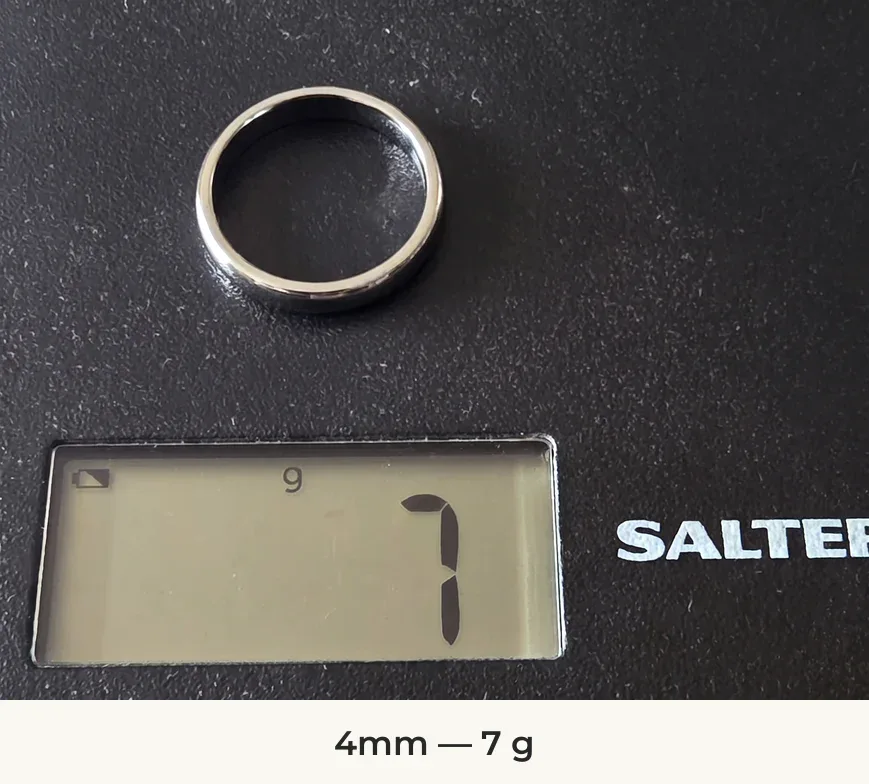 The Elie Thin Style 4mm silver-coloured tungsten ring on a Salter scale reading 7 g