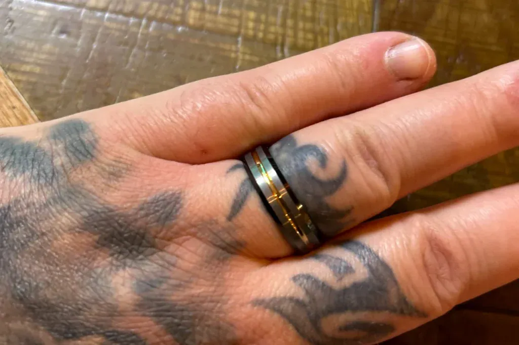 A customer's Champion tungsten ring on his tattooed ring finger after months of motorway and truck maintenance work, with no visible marks