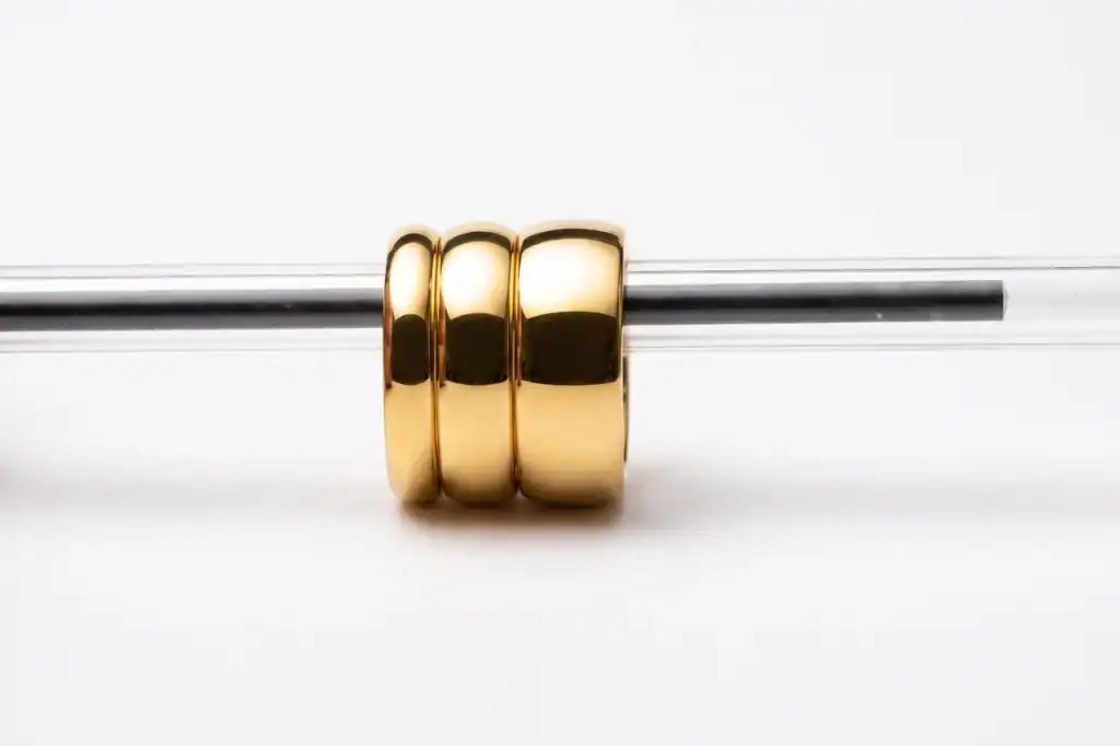 Edge-on view of 4mm, 6mm and 8mm gold tungsten rings threaded on a pen, showing the matching domed comfort-fit profile at every width